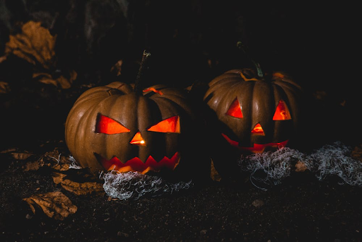 Two carved pumpkins with scary faces lit up in the dark